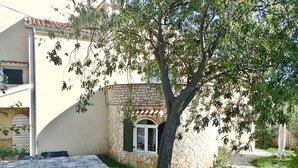 Ein Gebäude mit einer Fassade aus Stein, einem Ziegeldach und einem kleinen Fenster mit grünen Fensterläden.