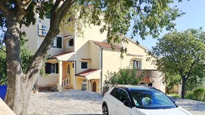 Ein weißer Volkswagen SUV steht auf einer Kopfsteinpflaster-Einfahrt vor einem zweistöckigen Gebäude mit einem Ziegeldach und einer Steinmauer.