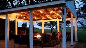 Un espace extérieur abrité, avec des tables et des chaises, un plafond en bois et des guirlandes lumineuses.
