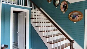 Una escalera con barandillas blancas y escalones de madera que conduce a una habitación con paredes color turquesa y una puerta.