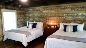 Une chambre avec deux lits, des murs en bois, une petite table avec une lampe et une fenêtre.