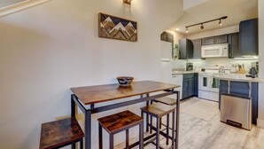 Une cuisine moderne avec des meubles de couleur sombre, un micro-ondes blanc et un réfrigérateur en acier inoxydable.