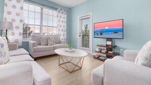 Un salon comprenant un canapé, un fauteuil, une table basse et un téléviseur posé sur un meuble.