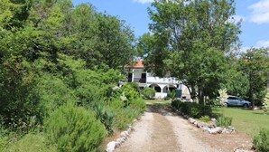 A pathway leading to a white building with arches, surrounded by lush greenery and a parked car. - Holiday apartment mit Klimaanlage (Šilo)