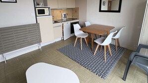 A compact kitchen with a dining area, including a table and chairs, a microwave, and a coffee maker. - Pornichet - Studio Place du Marché (PORNICHET)