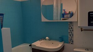 A bathroom with a white sink, blue walls, a mirror, and a toilet. - Pornichet - Studio Place du Marché (PORNICHET)