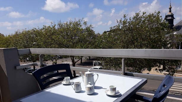 A table set for tea on a balcony with a view of trees and a building in the background. - Pornichet - Studio Place du Marché (PORNICHET)
