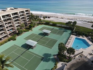 Relax by the pool or enjoy a game of tennis amidst lush greenery and palm trees, with the ocean views from your balcony.