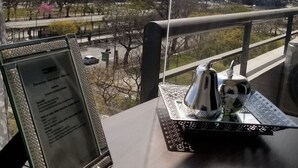 Une table avec un menu, un objet décoratif et une vue sur un paysage urbain avec des bâtiments et un pont.
