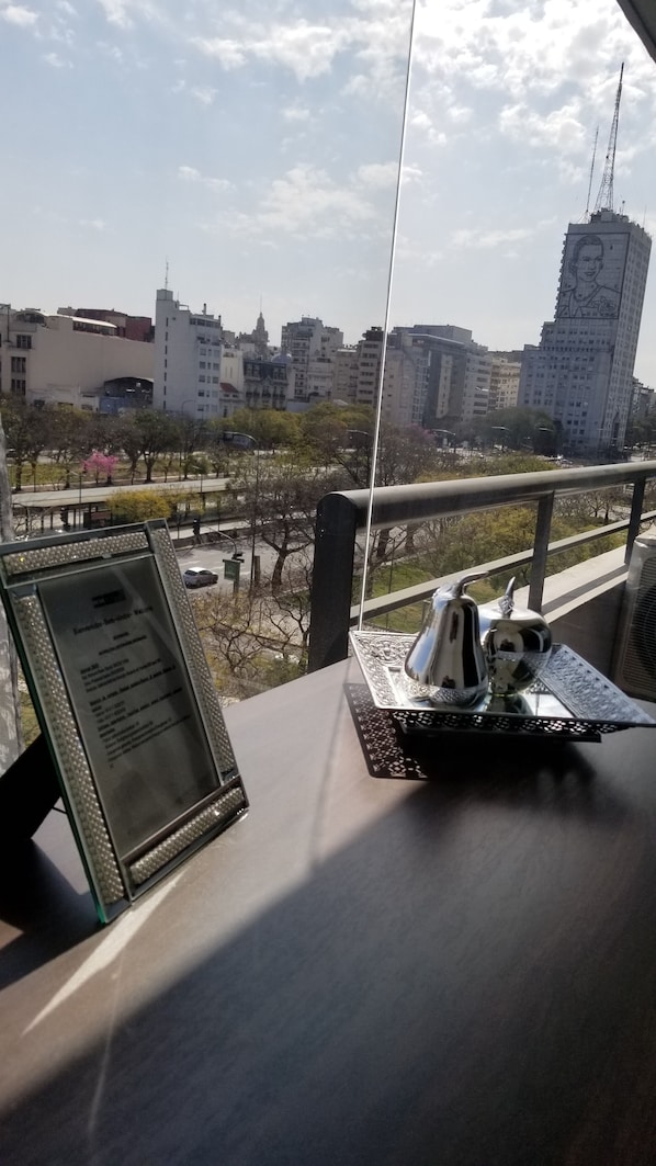 A table with a menu, a decorative item, and a view of a cityscape with buildings and a bridge.