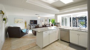 A spacious kitchen with a large island, white cabinetry, and a view of the outdoors. - Pool Home in Fort Meyers (Fort Myers)