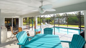 A covered outdoor area with a pool, chairs, and a table. - Pool Home in Fort Meyers (Fort Myers)