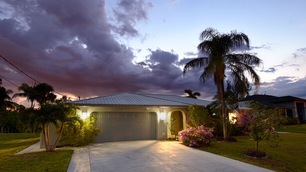 A residential house with a garage, surrounded by well-maintained lawns and flowering plants. - Pool Home in Fort Meyers (Fort Myers)
