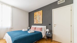Ein Schlafzimmer mit einem Bett, einem Nachttisch, einer Tür und einem Bild an der Wand.