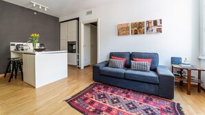 Ein modernes Wohnzimmer mit Kücheninsel, einer Couch mit gemusterten Kissen und Bildern an der Wand.