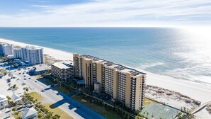 A high-rise hotel with multiple floors, a parking garage, and a beach view.