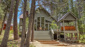 A cabin with a staircase leading to a deck, surrounded by tall trees. - Ponderosa Pine Escape  (Truckee)