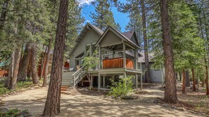 A two-story cabin with a balcony, surrounded by tall pine trees. - Ponderosa Pine Escape (Truckee)
