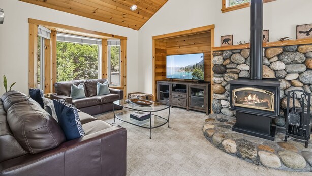 Una sala de estar acogedora con chimenea de piedra, sofá de cuero y televisor.