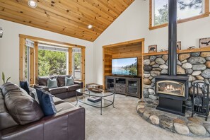 Ein gemütliches Wohnzimmer mit Kamin aus Stein, einer Ledersofa und einem Fernseher.