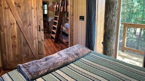 A rustic wooden room with a bed, a ladder, and a view of the outdoors. - Cherry Treesort "Trevor's Layaway" (China Grove)