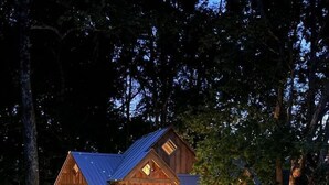 A wooden cabin with a deck, a staircase, and a bench. - Cherry Treesort "Trevor's Layaway" (China Grove)