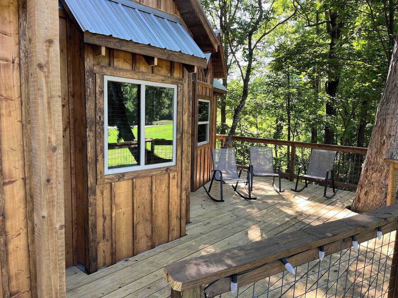 A wooden cabin with a deck, large windows, and outdoor seating.
