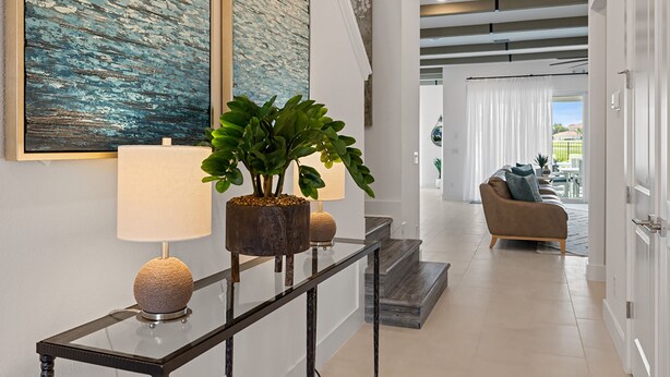 A modern interior with a glass console table, a potted plant, and a sofa in the background. - Imagination at Reunion | 9 BR, Custom Built Theme Room, Game Room, Movie Theater (Kissimmee)