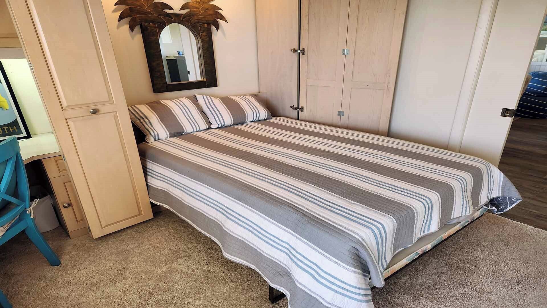 Un dormitorio con cama, armario y espejo.