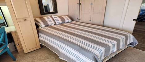 Un dormitorio con cama, armario y espejo.