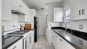 Eine moderne Küche mit weißen Schränken, einer schwarzen Arbeitsplatte und einem Edelstahlspülbecken.