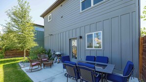 Une terrasse avec une table et des chaises, un barbecue et une clôture en bois.