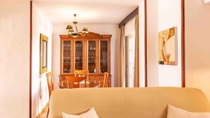 Ein Wohnzimmer mit einer Couch, einer Holzkabine mit Glastüren und einem Esstisch mit Stühlen.