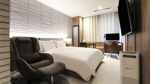 Une chambre d’hôtel moderne équipée d’un grand lit, d’un fauteuil inclinable, d’un bureau et d’un téléviseur à écran plat.