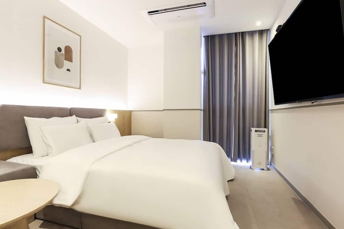 A hotel room with a bed, bedside table, and a TV.