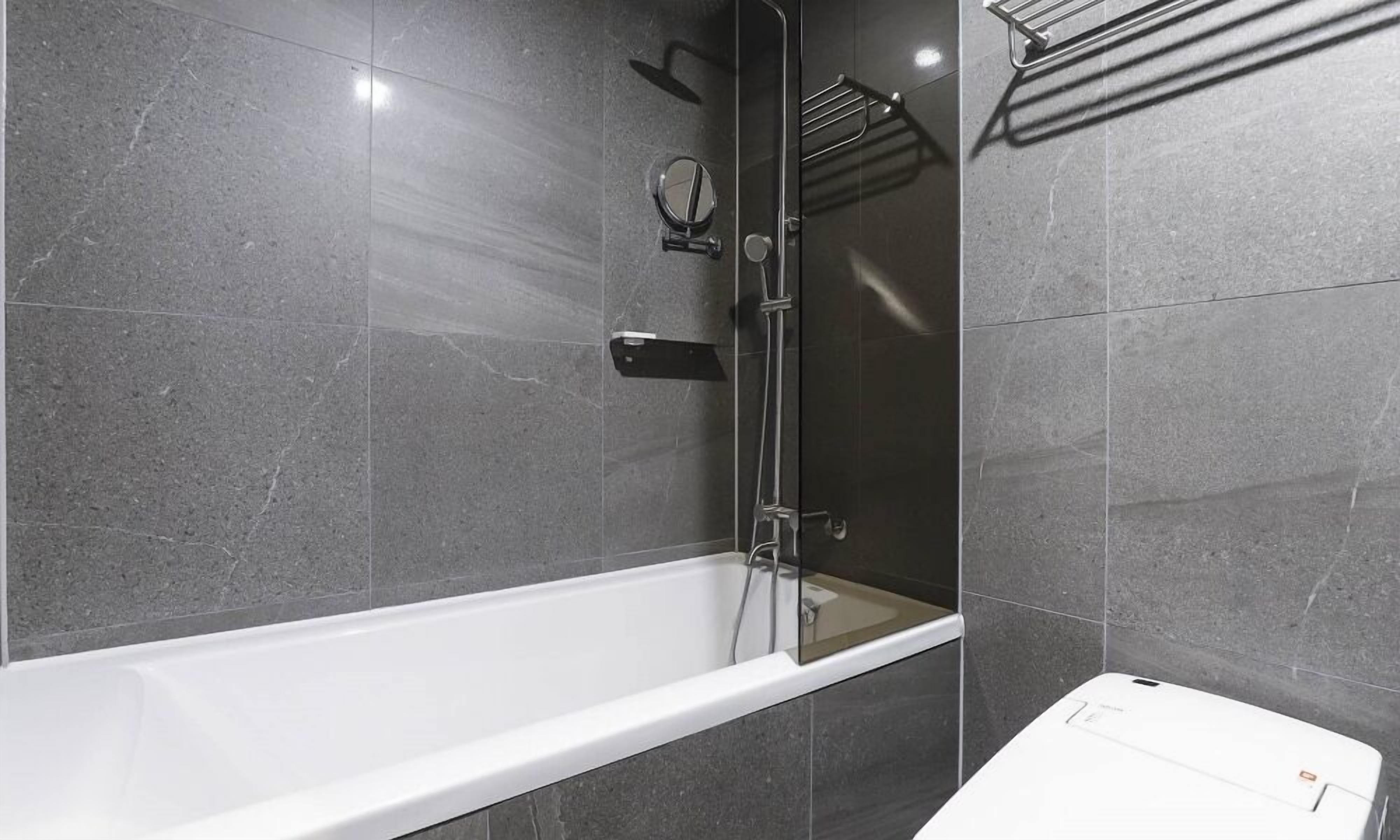 Ein modernes Badezimmer mit einer weißen Badewanne, einer Duschkabine und einem Handtuchhalter.