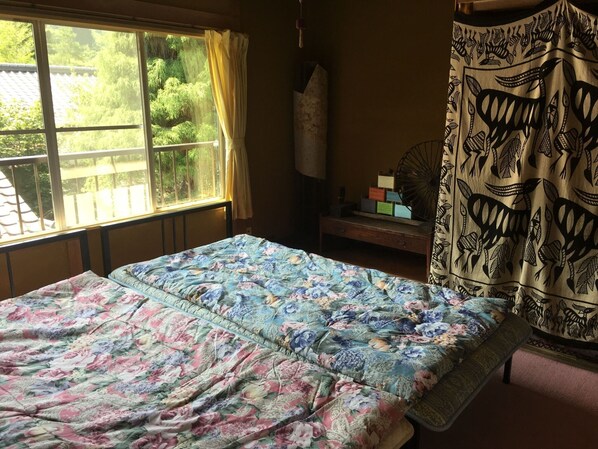 Un dormitorio con cama, una ventana con cortinas, una mesita de noche y cortinas estampadas.