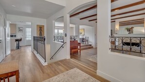 Un interior amplio con una escalera de madera, un comedor y una cocina visible al fondo.