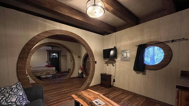 Een gezellige kamer met houten vloeren, een ronde tafel, een bank en een rond raam.