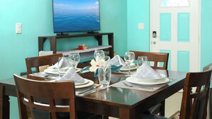A dining table set with plates, glasses, and cutlery, a flower centerpiece, and a television mounted on the wall.