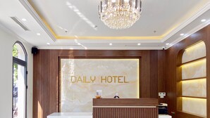 A reception desk with a marble wall backdrop and the text "DAILY HOTEL". - Daily Hotel (Bai Chay)