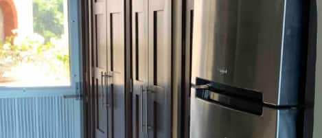 A kitchen with a stainless steel refrigerator, a water dispenser, and a door with a window.