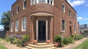 A two-story brick building with a curved facade, a central entrance with steps, and potted plants in front. - Story Bank Mandurama   (Mandurama)