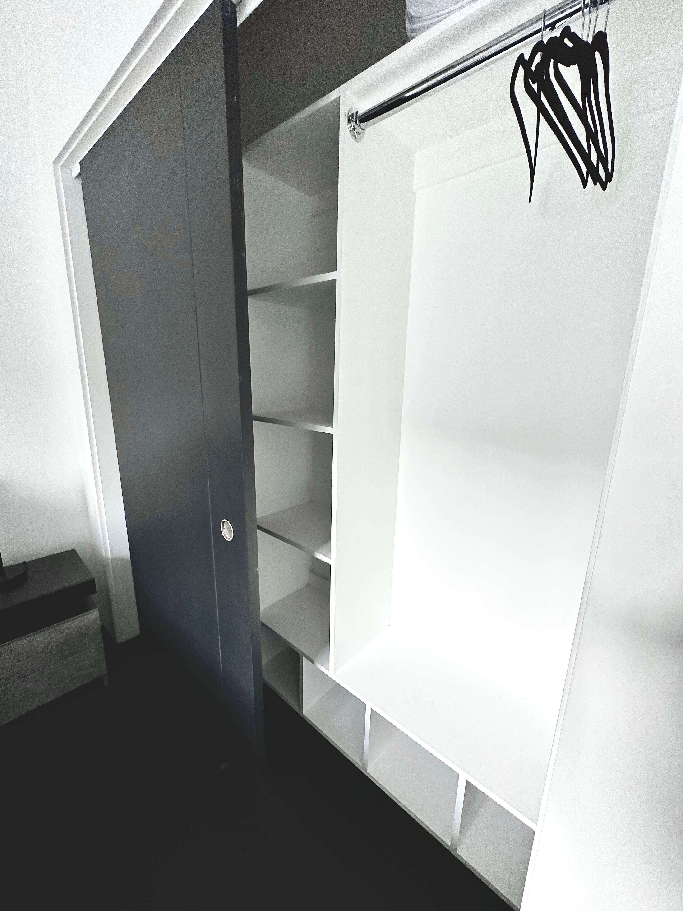 Ein begehbarer Kleiderschrank mit offenen Regalen und einer Kleiderstange.