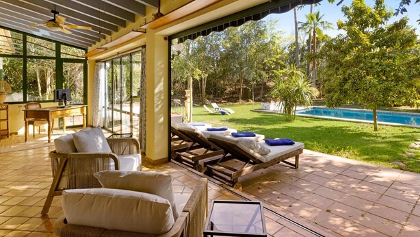 Un espace de détente extérieur abrité, doté de chaises longues et offrant une vue sur la piscine.