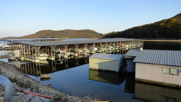 A marina with docked boats, a covered boat storage area, and a building with a corrugated metal roof.