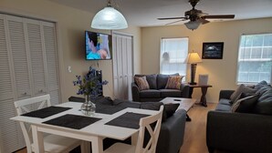A living room with a dining table, chairs, a sofa, and a TV.
