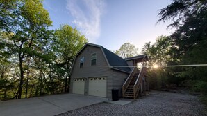 A two-story building with a garage, a staircase to the upper level, and a gravel driveway.