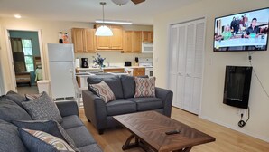 A modern living room with a grey sectional sofa, a wooden coffee table, and a television mounted on the wall.