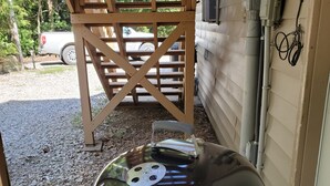 A barbecue grill with a lid, positioned outdoors near a wooden structure and a house.